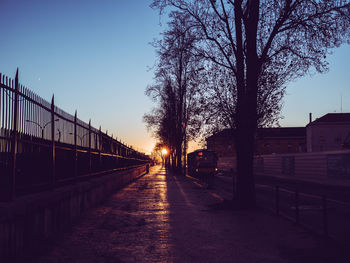 Street amidst trees against sky at dusk