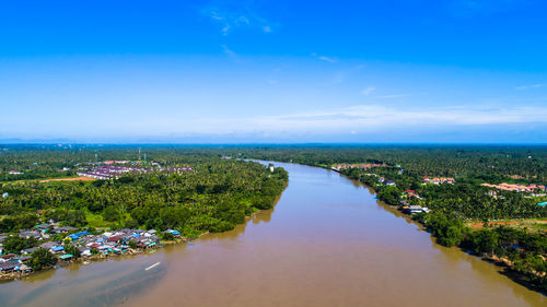 Scenic view of river amidst trees against blue sky