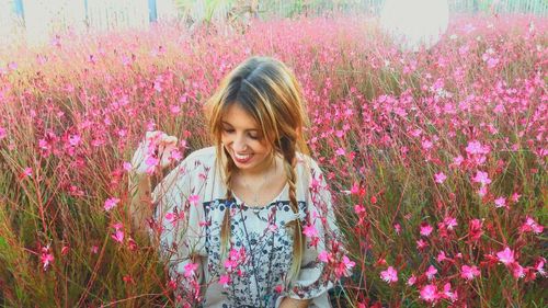 Happy woman amidst pink flowers at park