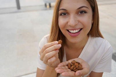 Portrait of smiling woman eating almonds outdoors