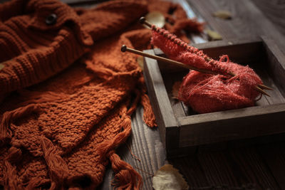 Cozy autumn background with knitted sweater scarf on a wooden background, with yellow birch leaves