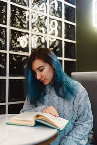 Young woman looking away while sitting on book