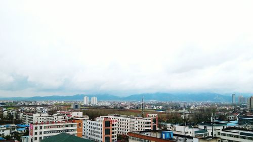 View of cityscape against cloudy sky