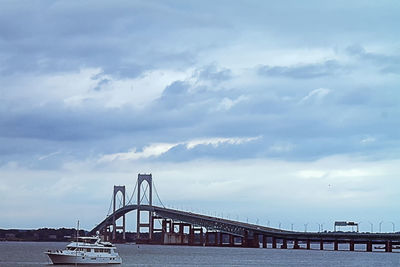 Bridge over calm sea against cloudy sky
