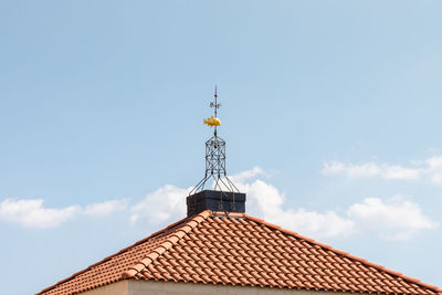 Low angle view of windmill on roof of building against sky