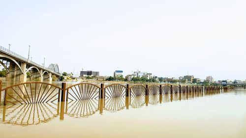 Bridge over river in city against clear sky