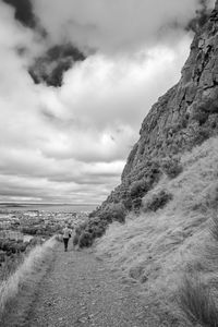 Man walking on mountain by sea against sky