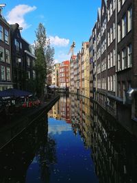 Reflection of buildings in canal against sky