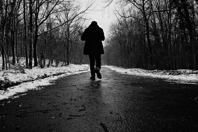Rear view of man walking on snow covered road