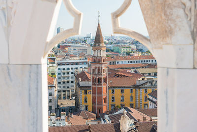 White statue on top of duomo cathedral and view to city of milan