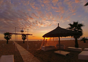 Built structure on beach against sky during sunset