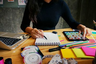 Midsection of woman using phone while sitting on table