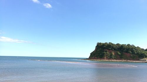 View of calm beach against blue sky