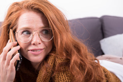 Woman using mobile phone while looking away in bedroom at home