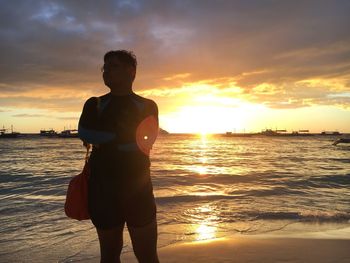 Silhouette woman standing at beach during sunset