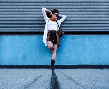 Woman with umbrella standing against wall