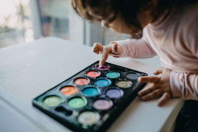 Midsection of girl touching paint in palette