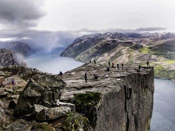 People on rock by mountain against sky