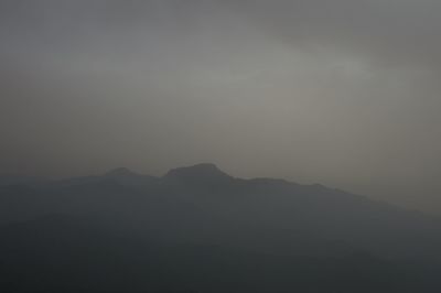 Silhouette of mountain range against cloudy sky