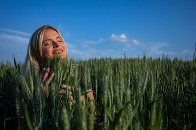 Portrait of young woman standing amidst plants against sky