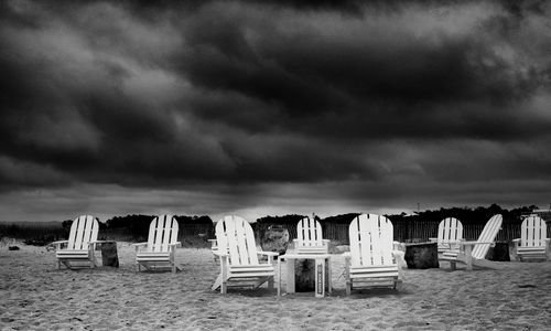 Hooded chairs on beach against sky