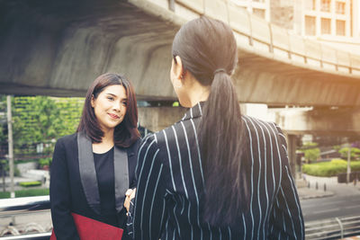 Smiling businesswoman handshaking with colleague in city 