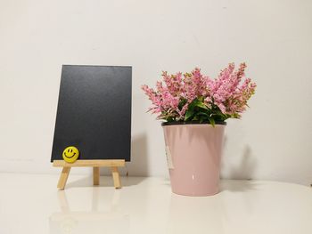 Flower vase by blackboard on table at home