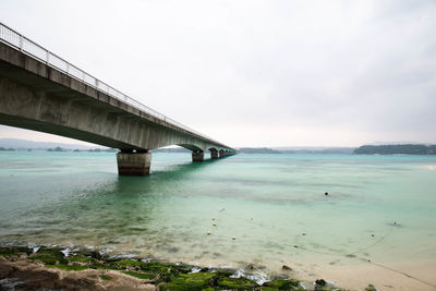 Bridge over calm sea against sky