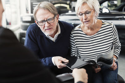 Senior couple looking at agreement in car dealership