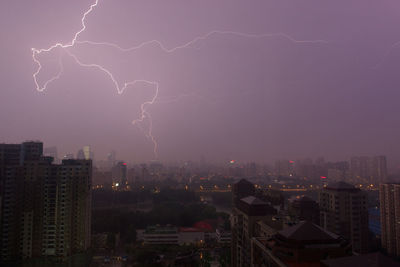 Lightning over cityscape against sky at night