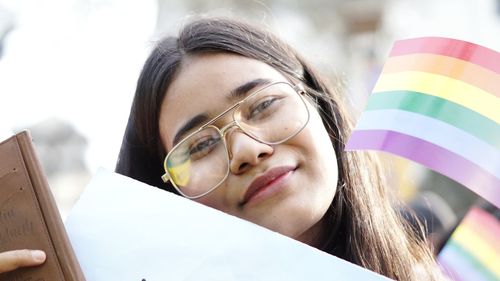 Portrait of smiling young woman with rainbow flags
