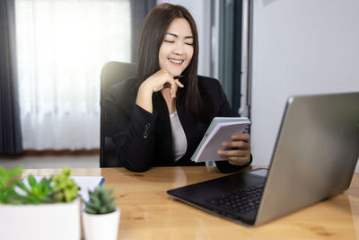 Young woman using phone on table