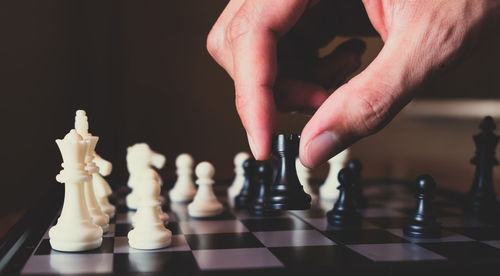 Low angle view of man playing with chess against black background