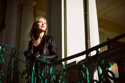 Portrait of young woman standing against railing