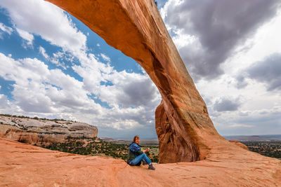 Woman on rock formation against sky