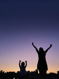 Silhouette woman with arms outstretched against sky during sunset