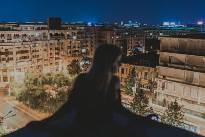 Rear view of woman standing against buildings in city