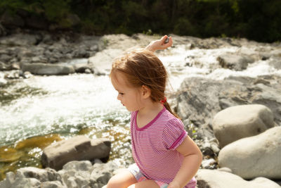 Side view of girl sitting on rock