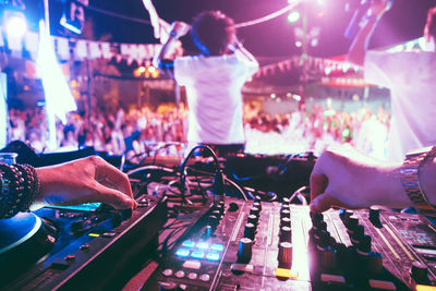 Cropped hands of dj playing sound recording equipment in club