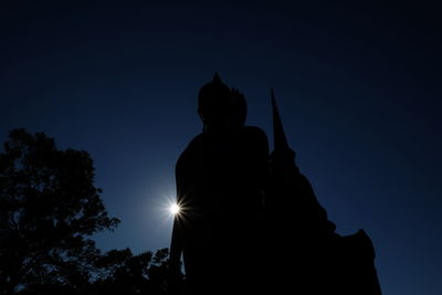 Low angle view of silhouette statue against sky