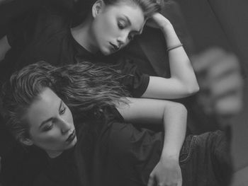 High angle view of female fiends lying on bed