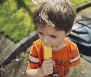 High angle view of boy eating popsicle while standing on road