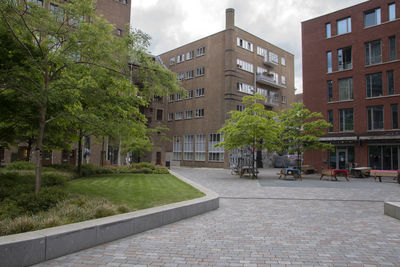 Street amidst trees and buildings against sky