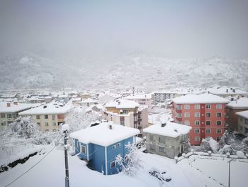 Snow covered houses by buildings against mountain