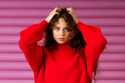 Portrait of young woman standing against curtain