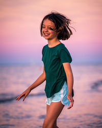 Happy woman on beach against sky during sunset