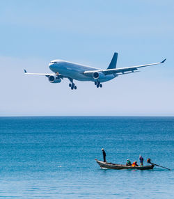 People kayaking on sea against sky