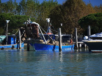 Fishing boats moored in river against sky