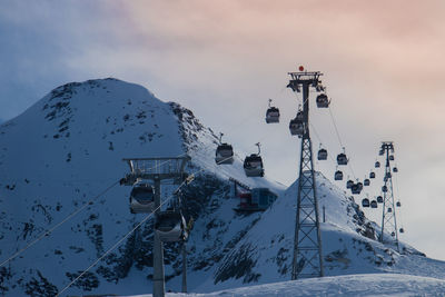 Gondola lift with background of snow covered mountain against sky