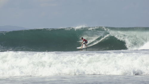 Man surfing in sea against sky